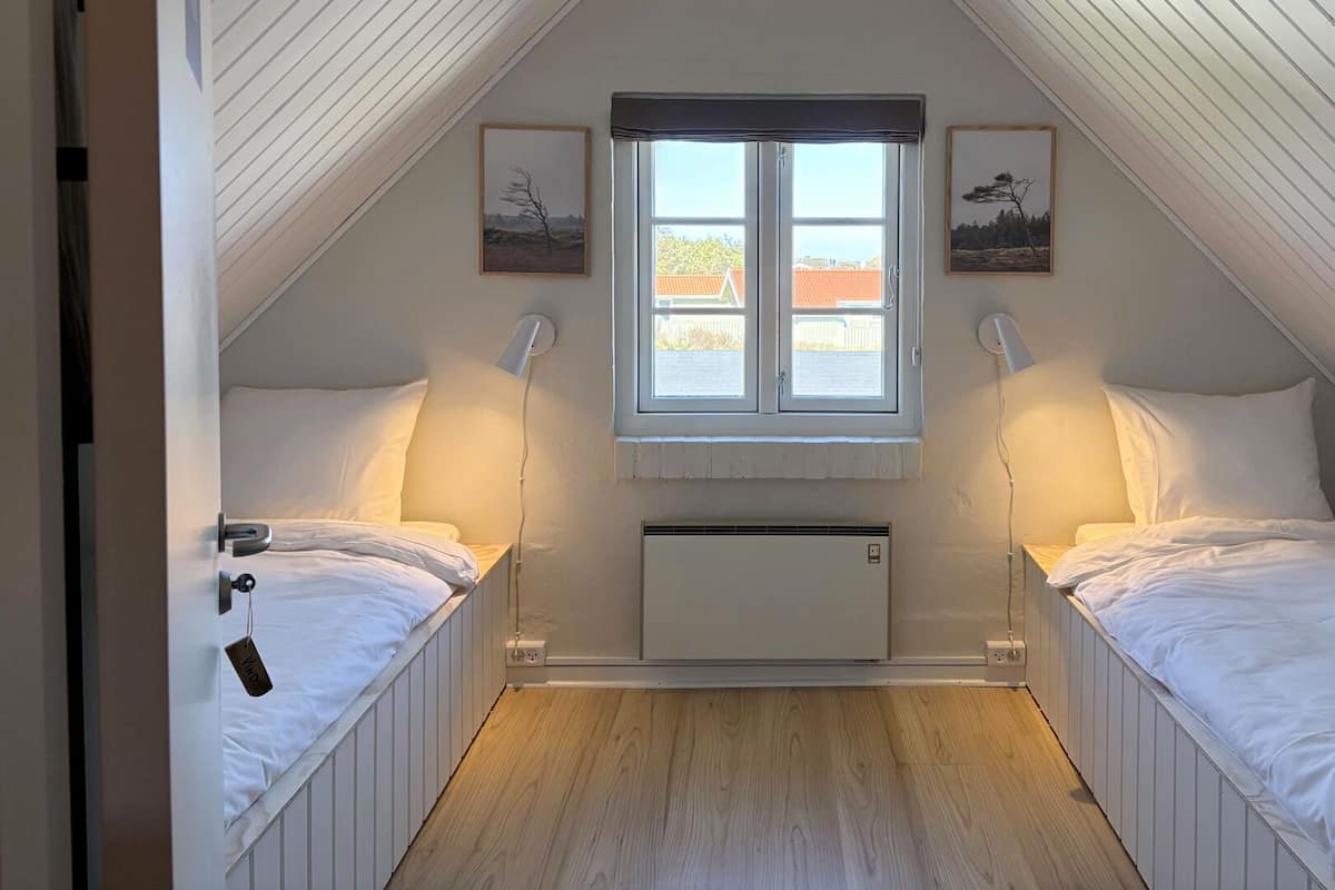 Une chambre avec deux lits, une fenêtre et un radiateur.