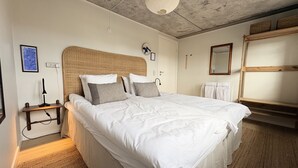 Una camera da letto con un letto grande, un comodino con una lampada, una sveglia a muro e un lampadario al soffitto.