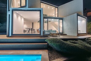 Una casa moderna con amplios ventanales, una piscina y un patio.