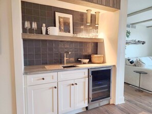 A modern kitchen with a built-in oven, a sink, and a countertop with a picture frame and glasses. - Sandpiper Run B1A - Beautiful Condo with 2 Kings (Pawleys Island)