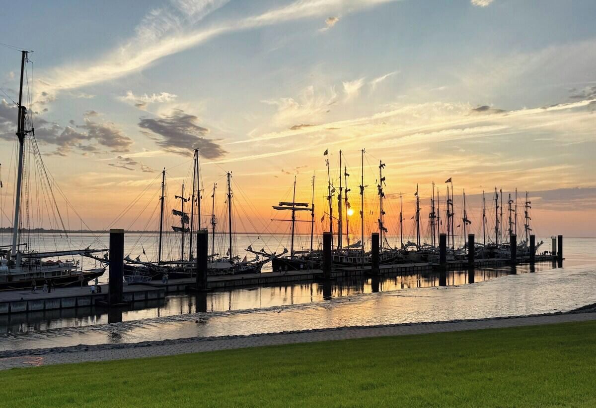 A marina with multiple boats docked at wooden piers during sunset.