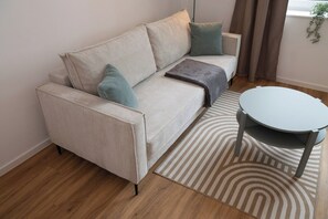 Un salon moderne avec un canapé, des coussins, une table basse ronde et un tapis à motifs.