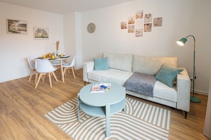 Ein Wohnzimmer mit rundem Tisch, einer Couch und einem Essbereich mit Stühlen.