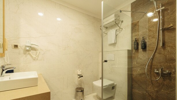 A modern bathroom with a glass-enclosed shower, a white sink, and a toilet. - Tolenza Hotels Alanya (Alanya)