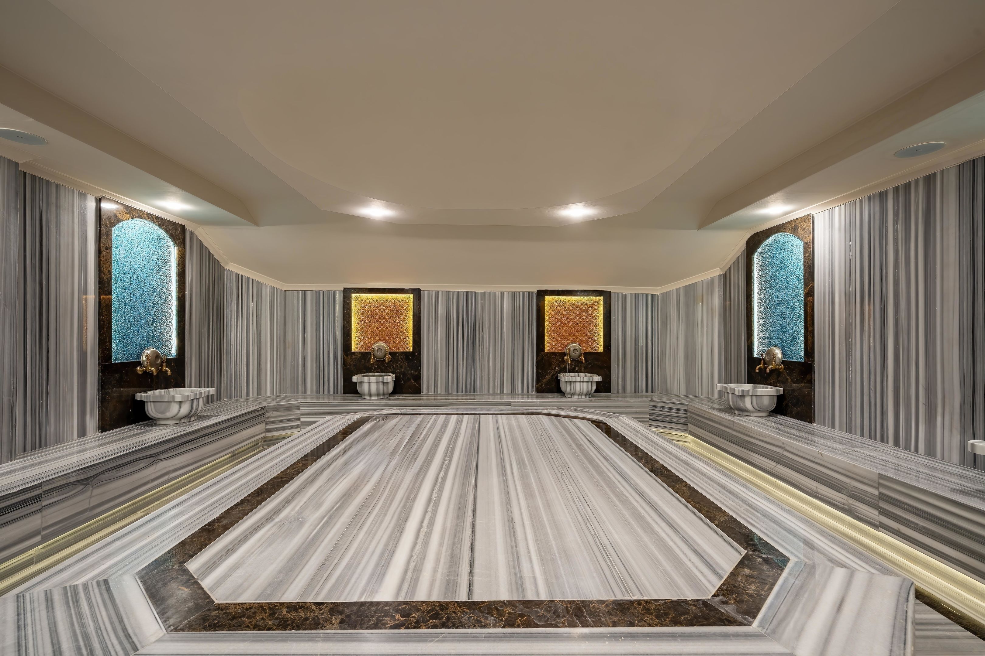 A spacious bathroom with marble flooring, large windows, and two sinks with gold fixtures.