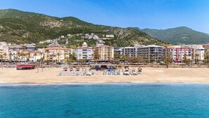 Un hôtel situé sur la côte, avec plusieurs étages, donnant sur la plage et offrant une vue sur la mer.