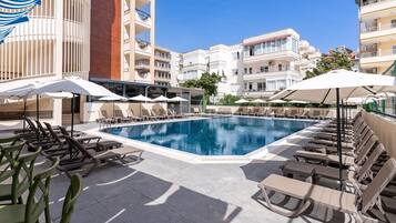 Una piscina al aire libre, sombrillas, sillones reclinables de piscina