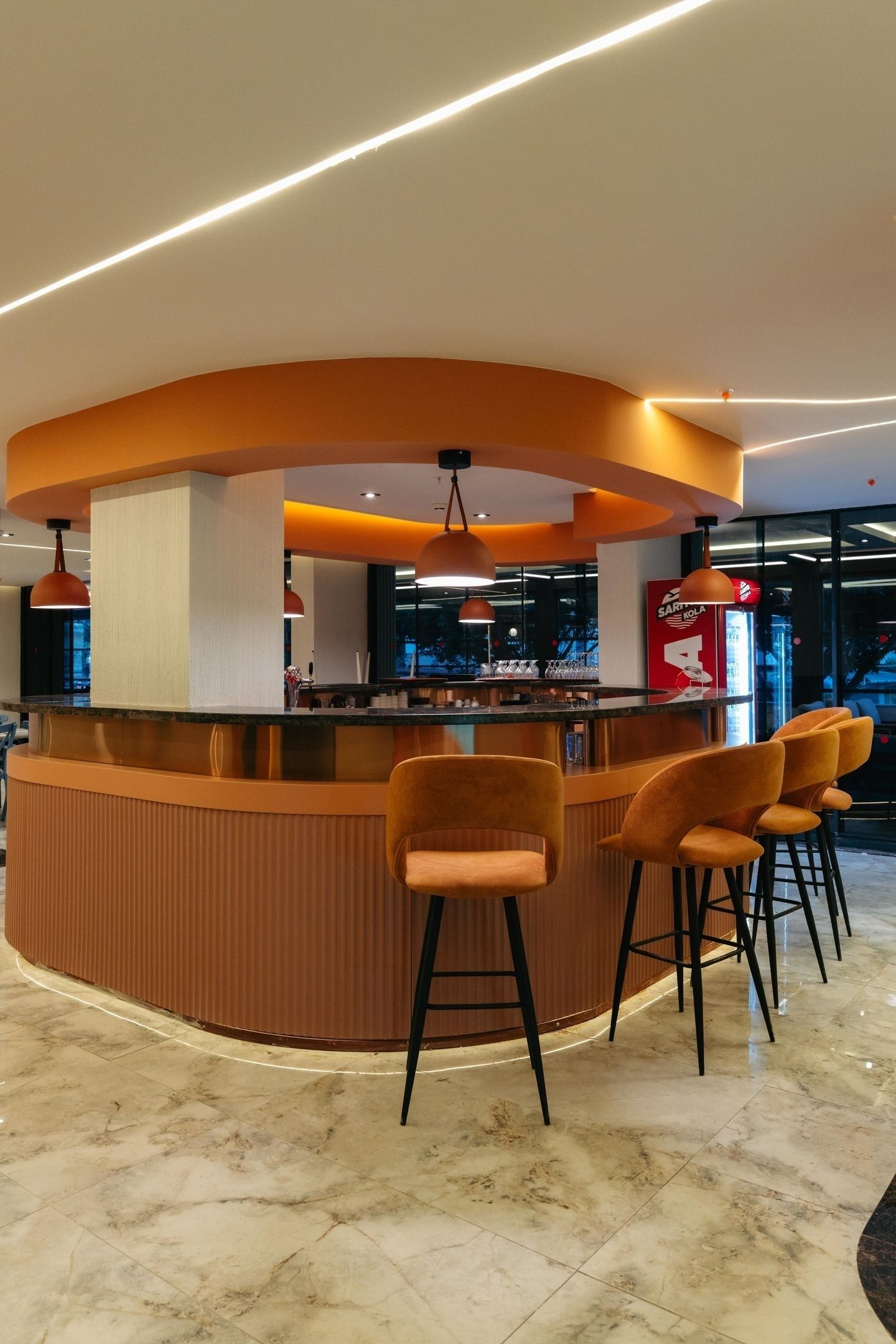 Un área de bar moderna con una barra curva, taburetes, iluminación colgante y un cartel visible de Minibar.