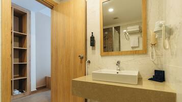 Un baño con puerta de madera, un lavabo, un espejo, un perchero para toallas y un teléfono.