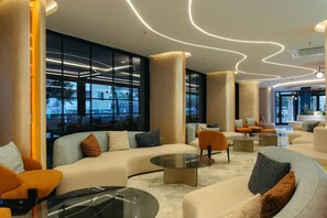 Een modern interieur met banken, fauteuils en een glazen salontafel.