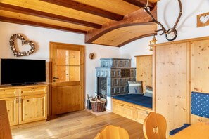 Un intérieur en bois comprenant une télévision, des meubles en bois, une cheminée et un lit avec un matelas bleu.