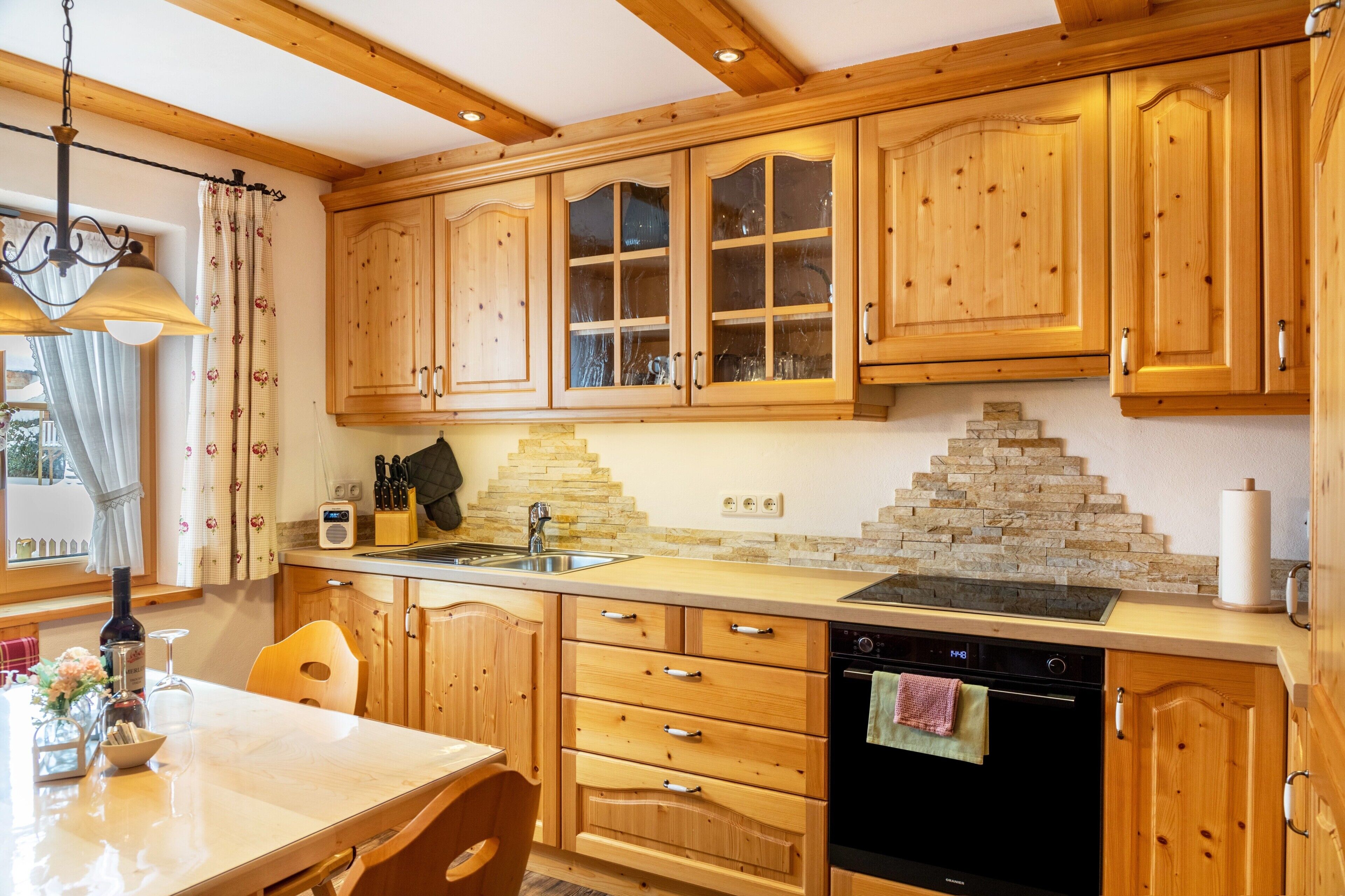 A kitchen with wooden cabinets, a built-in oven, and a stone backsplash.