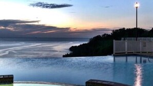 En pool med udsigt til havet i solnedgang.