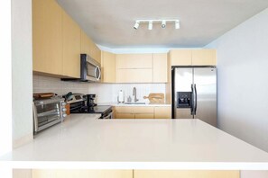 A modern kitchen with a stainless steel refrigerator, a built-in oven, and a microwave.
