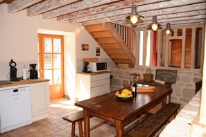 Une cuisine rustique avec une table en bois, un mur en pierre et un escalier.