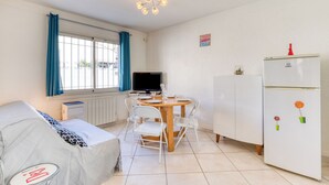 En kompakt opholdsstue med spiseplads, sofa, fjernsyn og køleskab.