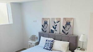 A modern bedroom with a large bed, a bedside table with a lamp, and two wall-mounted artworks. - Eidolion Essence Nest - Mykonos Cozy Getaway (Mykonos)