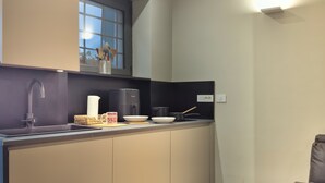 Una cocina compacta de diseño moderno, con un lavamanos, una cafetera y una ventana sobre la encimera.