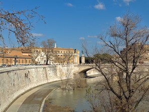 A river with a stone bridge, a building with classical architecture, and bare trees. - Il Borghetto old Town gem (Rome)