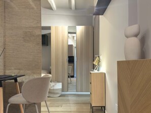 A modern, minimalist room with a wooden floor, a desk with a lamp, a chair, and a large abstract sculpture on the wall. - Il Borghetto old Town gem (Rome)