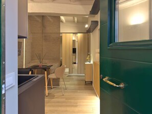 A modern kitchen with a dining area, a wooden floor, and a green door. - Il Borghetto old Town gem (Rome)