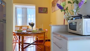 Una cocina con microondas, una mesa de comedor con sillas y un florero con flores.