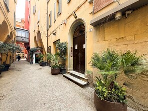 A narrow cobblestone alley with potted plants and a building entrance. - Loft Piazza Maggiore Comfort in the City Center (Bologna)