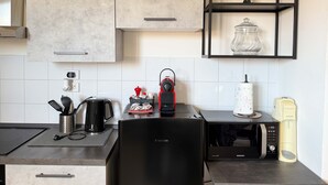 A modern kitchen with a black refrigerator, a microwave, a coffee maker, and a shelf with a decorative item. - Cinzia s City Pad Comfort Near Central Station (Bologna)