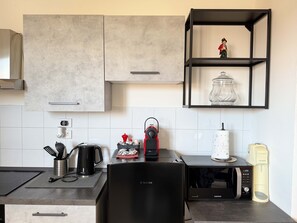 A modern kitchen with a black refrigerator, a microwave, a coffee maker, and a shelf with a decorative item. - Cinzia s City Pad Comfort Near Central Station (Bologna)