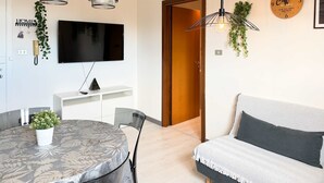 A modern living room with a round dining table, a sofa, and a TV mounted on the wall. - Cinzia s City Pad Comfort Near Central Station (Bologna)