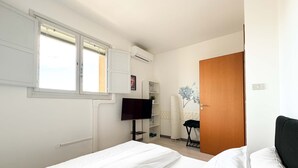 A bedroom with a bed, a TV, a wardrobe, and a window. - Cinzia s City Pad Comfort Near Central Station (Bologna)