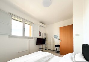 A bedroom with a bed, a TV, a wardrobe, and a window. - Cinzia s City Pad Comfort Near Central Station (Bologna)