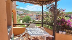 Ein Balkon mit Tisch und Stühlen mit Blick auf eine Wohngegend, gesäumt von Häusern und Grünflächen.