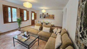 Ein Wohnzimmer mit einem Ecksofa, einem Glastisch und einer Chandelier.