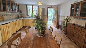 Eine Küche mit Holzausstattung, einem Esstisch, Stühlen und Topfpflanzen.