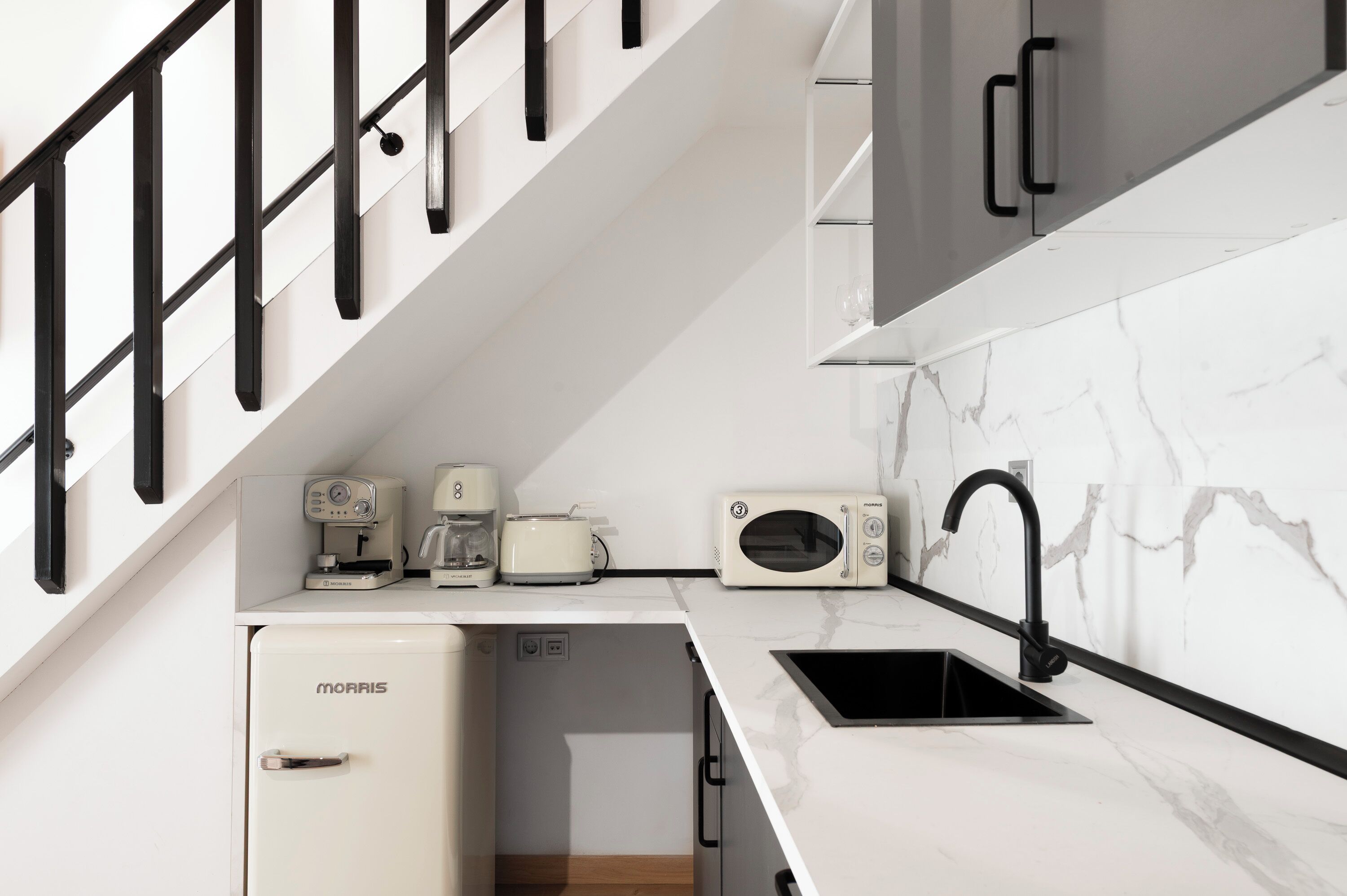 A compact kitchen with a refrigerator, a coffee maker, a toaster, a microwave, and a sink.