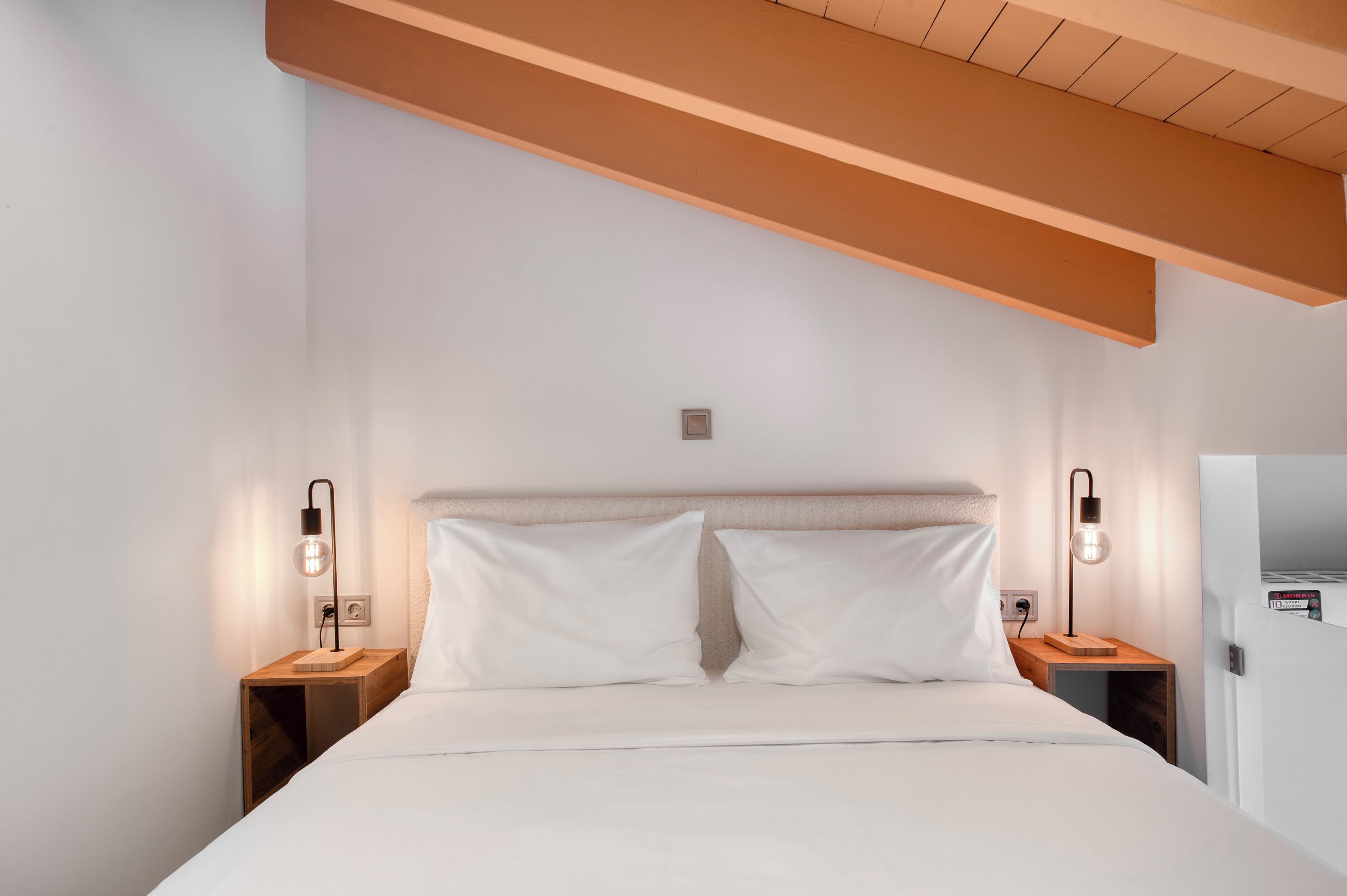 A bedroom with a bed, two bedside tables, and two wall-mounted lamps.