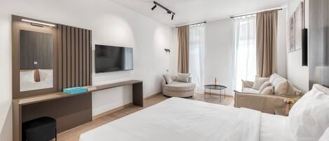 A hotel room with a bed, a desk, a TV, a chair, and a small table with a bottle and glasses.