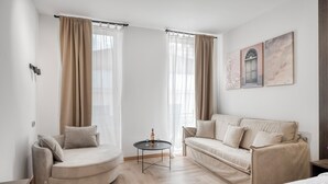 A modern room with a curved sofa, a small round table, and a bed. - Athenian Heart Suites  (Athens)