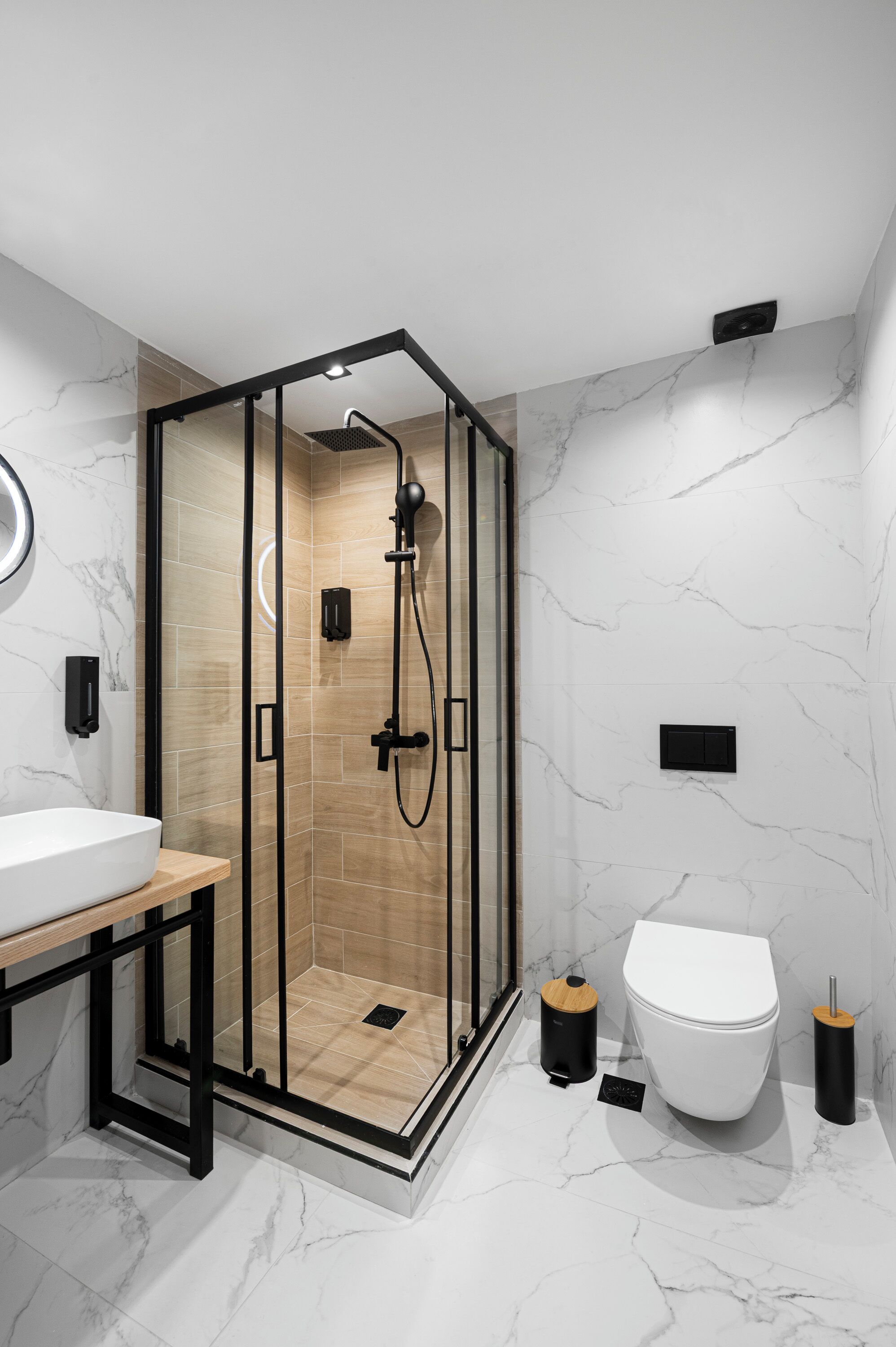Ein modernes Badezimmer mit einer Duschkabine aus Glas, einem weißen Waschbecken und einer Toilette.