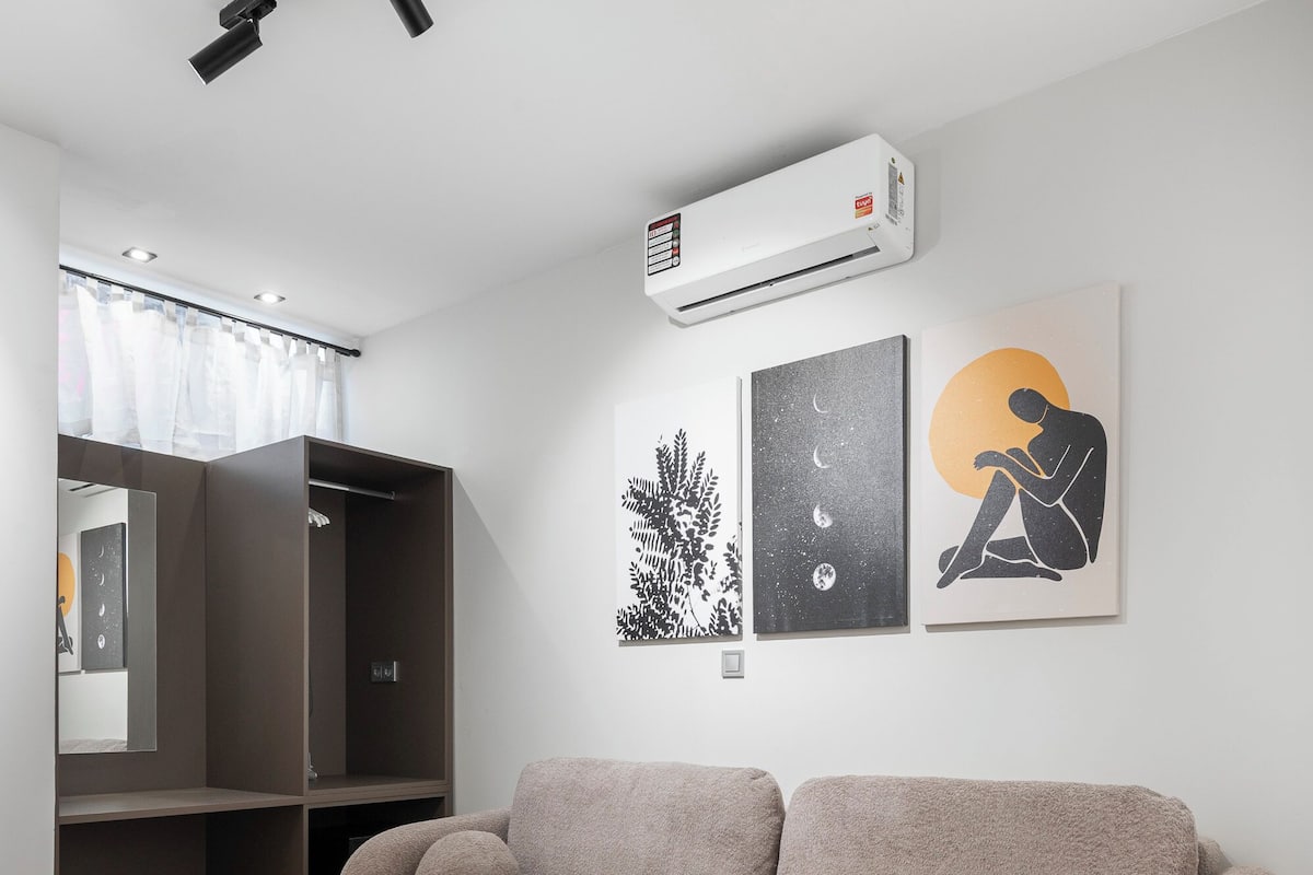 A modern living room with a sofa, a round coffee table with fruit, a wardrobe, and wall art.