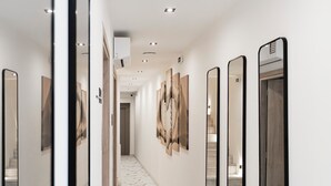 A hallway with marble flooring, multiple mirrors, and a staircase in the background. - Athenian Heart Suites  (Athens)