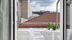 A balcony with white chairs, a table, and a potted plant. - Athenian Heart Suites  (Athens)