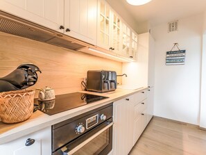 A modern kitchen with white cabinets, a built-in oven, a coffee maker, and a kettle on the countertop. - Lovely apartment for 4 guests with WIFI, TV and pets allowed (Blankenberge)