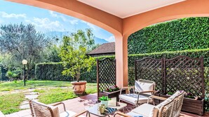 Une terrasse avec des meubles d’extérieur, une plante en pot et une vue sur un jardin et des montagnes.