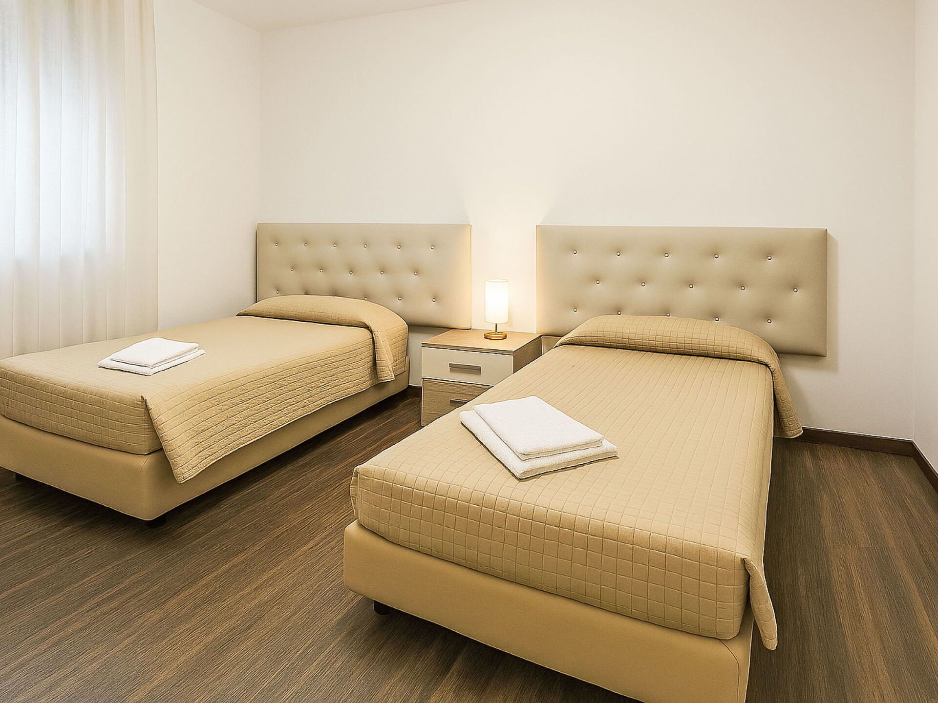 Een hotelkamer met twee bedden, een nachtkastje en een lamp.