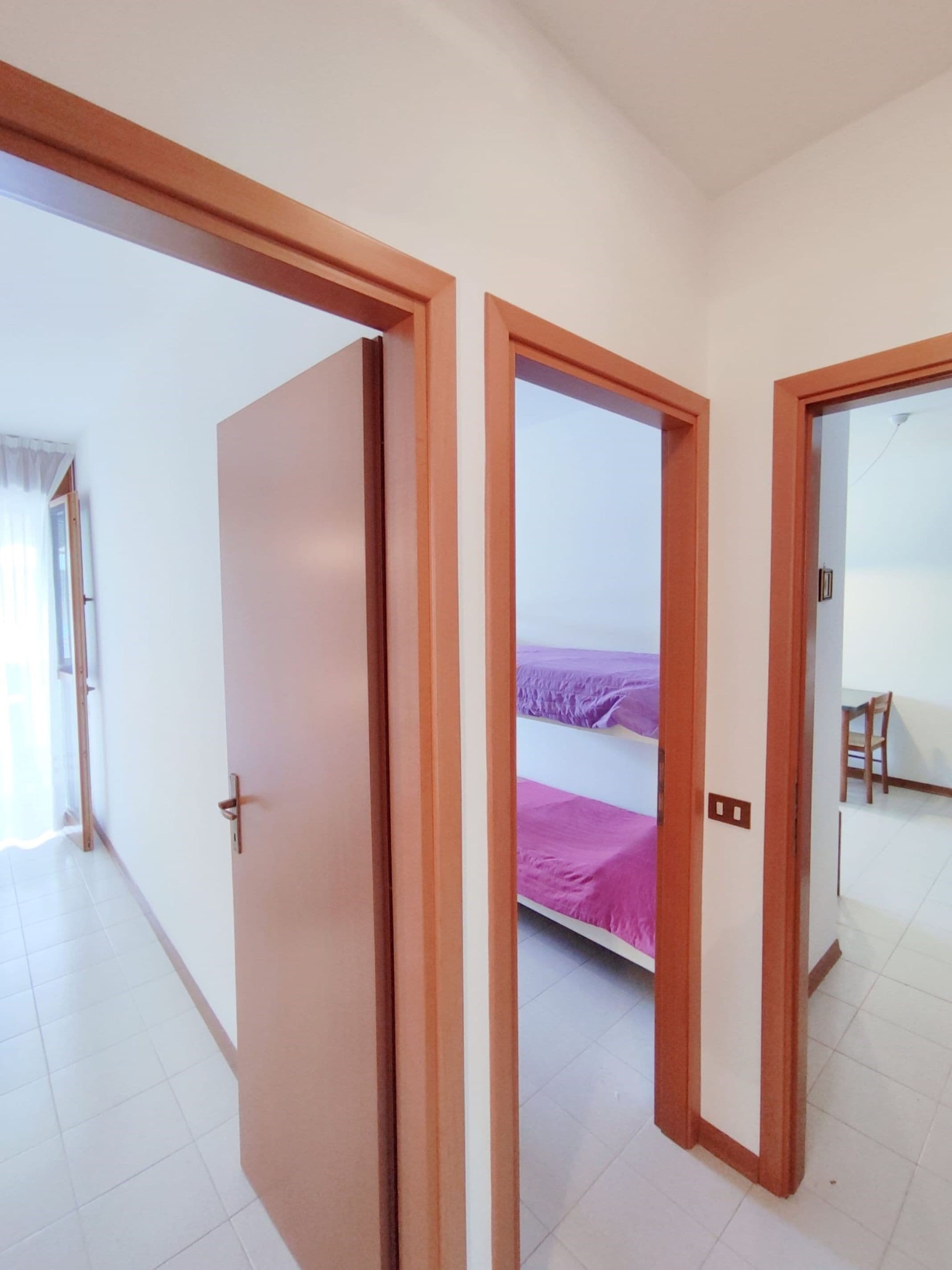 A room with a bed, a chair, and a door.
