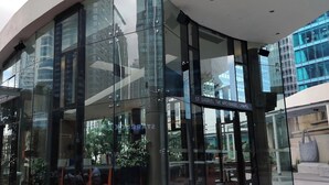 A modern building with large glass windows and a curved facade. - Modern 1BR Condo in BGC One Uptown Near Uptown Mall Landers Mitsukoshi Mall Wifi (Taguig)