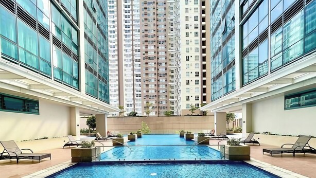 A swimming pool with lounge chairs and a view of tall residential buildings. - Modern 1BR Condo in BGC One Uptown Near Uptown Mall Landers Mitsukoshi Mall Wifi (Taguig)