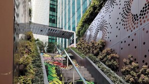 A staircase with colorful steps and a metal railing, surrounded by greenery and a building with a patterned wall. - Modern 1BR Condo in BGC One Uptown Near Uptown Mall Landers Mitsukoshi Mall Wifi (Taguig)